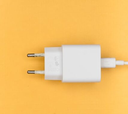 Na żółtym tle znajduję się biała ładowarka do sprzętu elektronicznego.